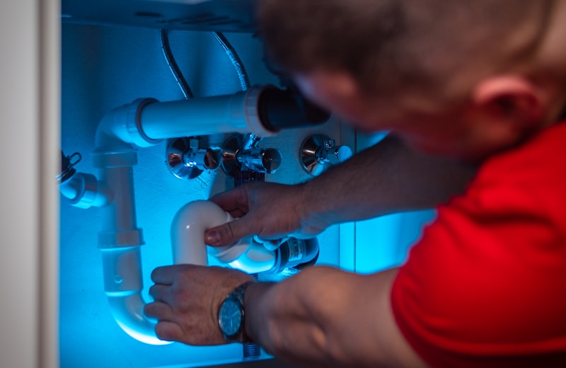 Plumber repairing pipework under a sink